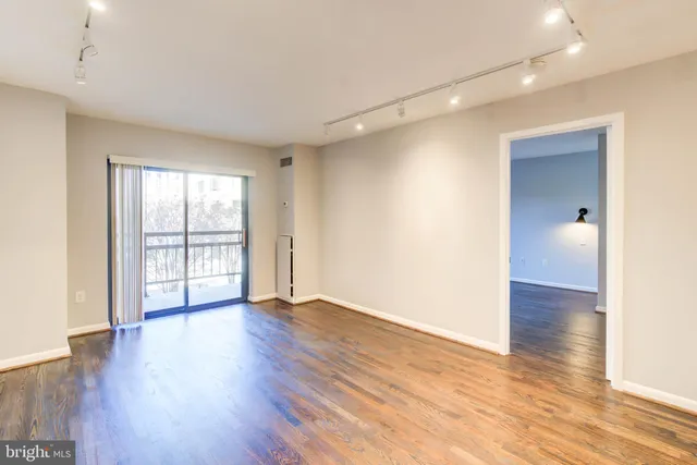a view of an empty room with wooden floor and a window