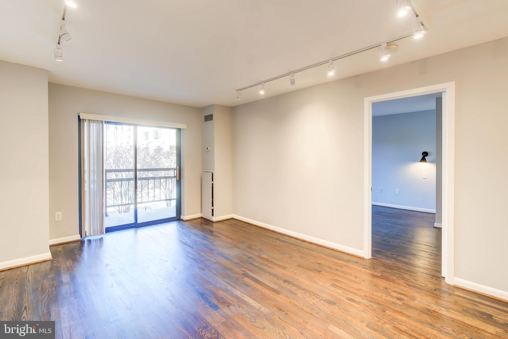 2111 Wisconsin Avenue Northwest, Unit 302 Washington, DC 20007 - Photo 7 of 23 a view of an empty room with wooden floor and a window
