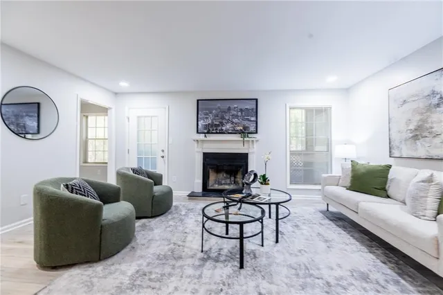 a living room with furniture a rug a fireplace and a large window