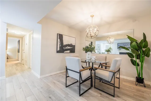a dining room with wooden floor a chandelier a glass table and chairs