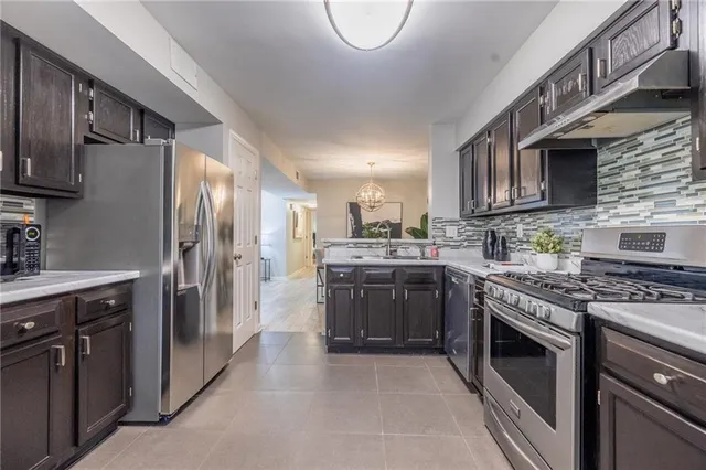 a kitchen with stainless steel appliances granite countertop a stove top oven a sink dishwasher a refrigerator and cabinets with wooden floor