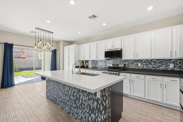 a kitchen with stainless steel appliances granite countertop a stove a sink and a refrigerator