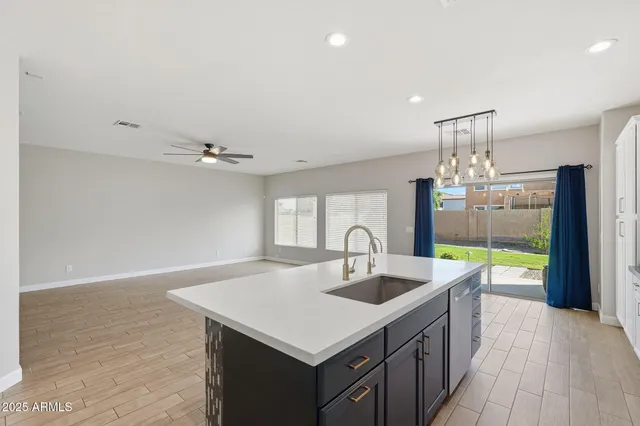 a kitchen with a sink chandelier and wooden floor