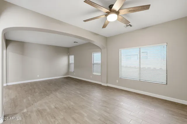 an empty room with chandelier fan and windows