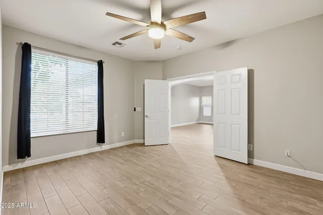 a view of empty room with wooden floor and fan