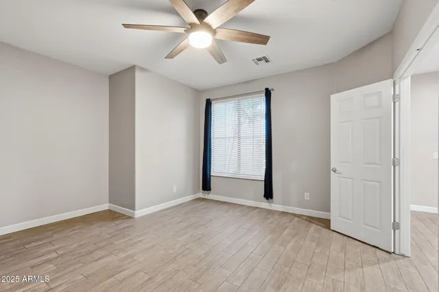 an empty room with wooden floor and ceiling fan