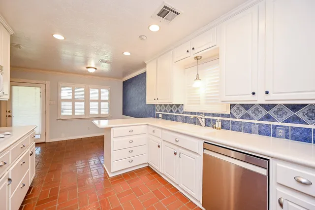 a kitchen with stainless steel appliances granite countertop a stove a sink and white cabinets with wooden floor