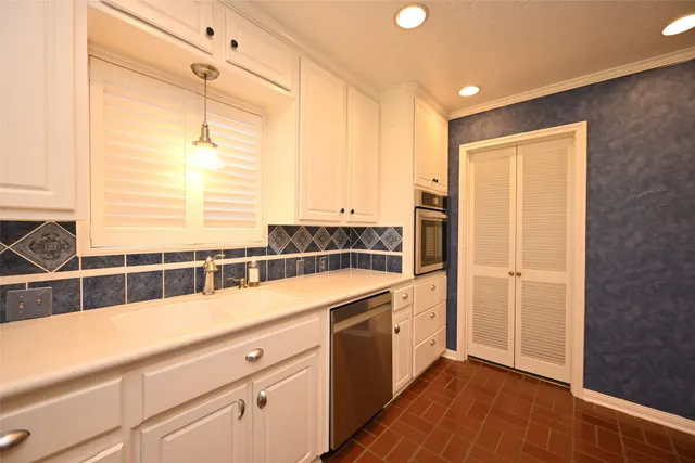 a view of a kitchen with a sink and dishwasher with white cabinets