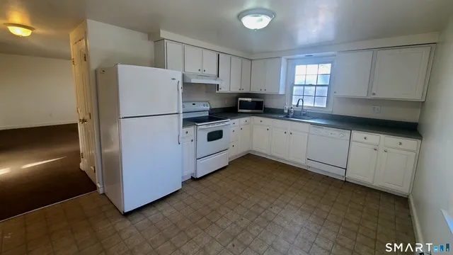 a kitchen with white cabinets and white appliances