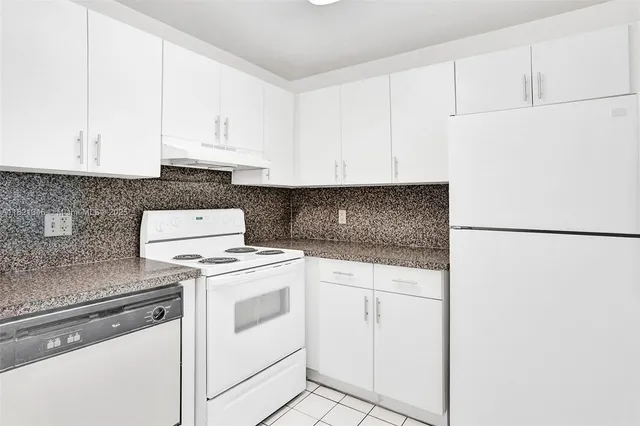 a kitchen with granite countertop white cabinets and white appliances