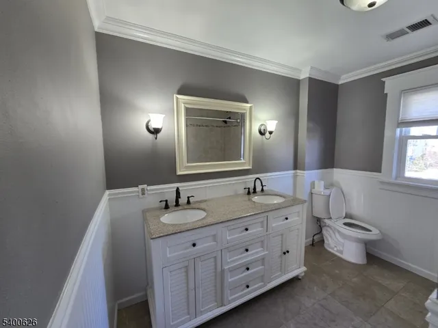 a bathroom with a double vanity sink and mirror with toilet