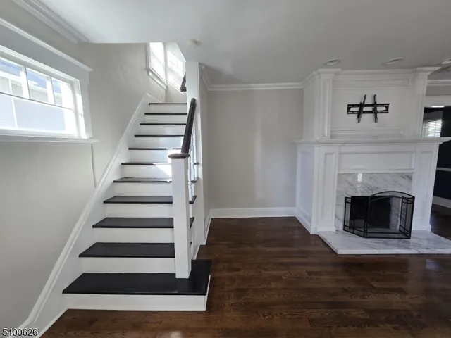 a view of an empty room with wooden floor fireplace and a window