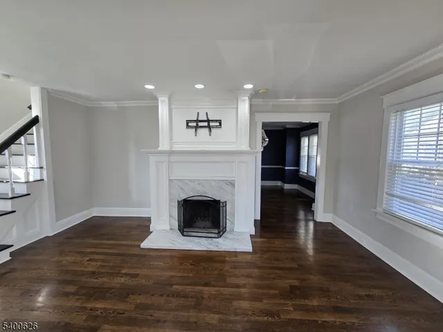 a view of an empty room with wooden floor fireplace and a window