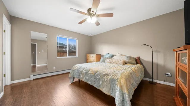a bedroom with a bed and a ceiling fan with wooden floor