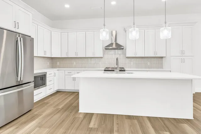a kitchen with kitchen island white cabinets and stainless steel appliances