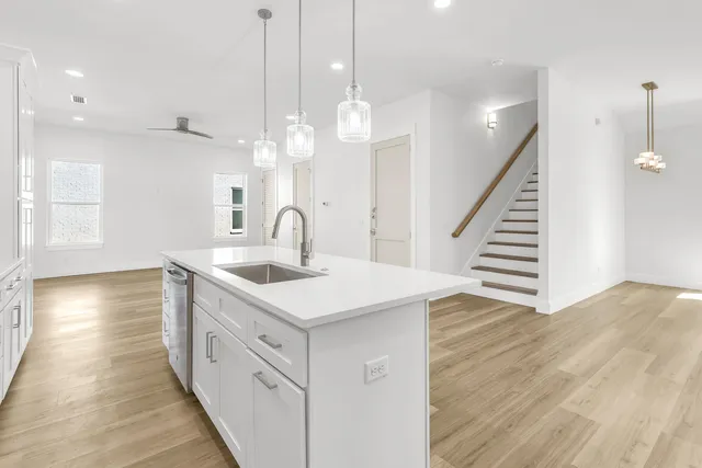 a kitchen with a sink a chandelier stainless steel appliances and cabinets
