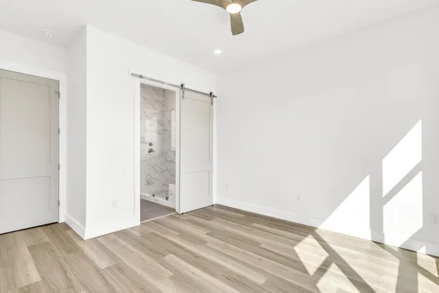 a view of empty room with wooden floor and fan
