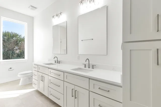 a bathroom with a double vanity sink toilet mirror and bathtub