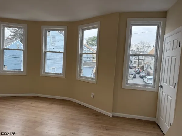 a view of an empty room with wooden floor and windows