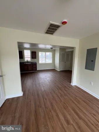 a view of a livingroom with wooden floor and a kitchen