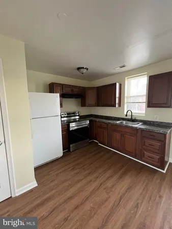 a kitchen with granite countertop a refrigerator and a stove top oven