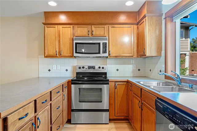 a kitchen with stainless steel appliances granite countertop a sink a stove a microwave cabinets and a counter top space