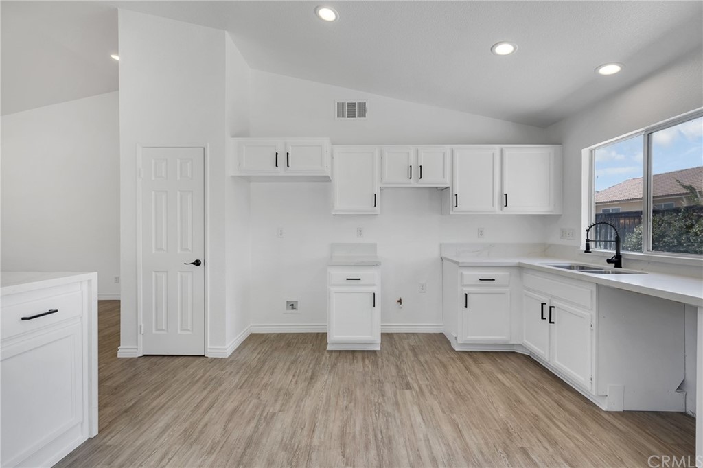 175 Paperbirch Circle Corona, CA 92881 - Photo 19 of 33 a kitchen with wooden floors and white cabinets