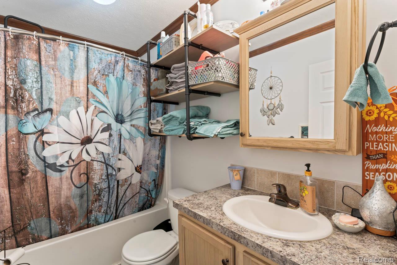 11141 Farrand Road Montrose, MI 48457 - Photo 17 of 51 Full bathroom with shower / bath combo with shower curtain, vanity, and a textured ceiling