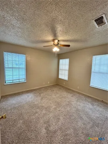an empty room with windows and ceiling fan view