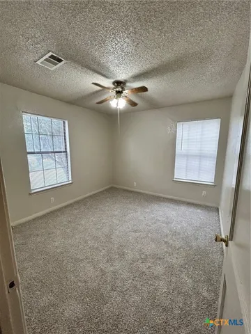 an empty room with windows and fan