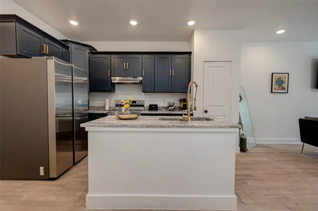 a kitchen with granite countertop a refrigerator and a stove top oven