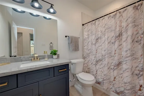 a bathroom with a granite countertop sink toilet and a mirror