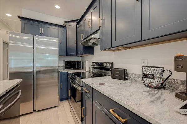 a kitchen with stainless steel appliances granite countertop a sink a stove and a refrigerator