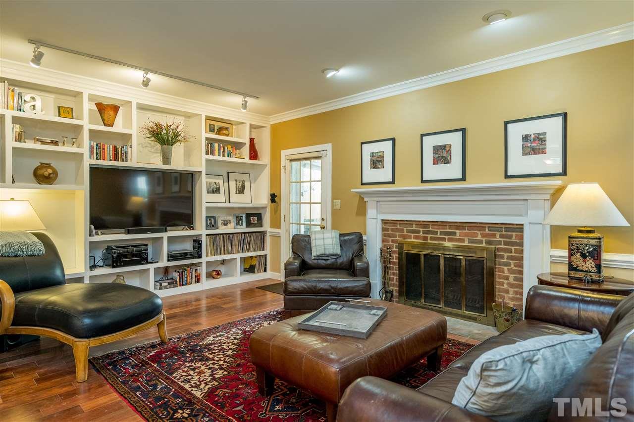 717 Weathergreen Drive Raleigh, NC 27615 - Photo 2 of 30 Custom designed built in wall of shelving with soundproofing in living room. Also note the wood burning fireplace.