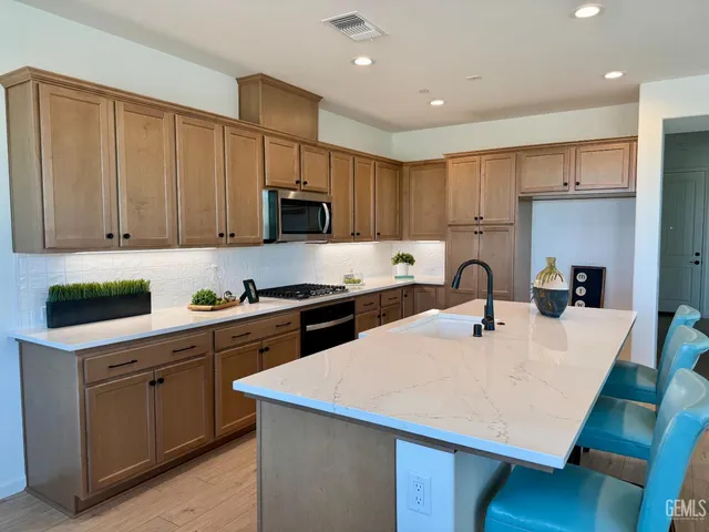 a kitchen with kitchen island a stove a sink a refrigerator and white cabinets