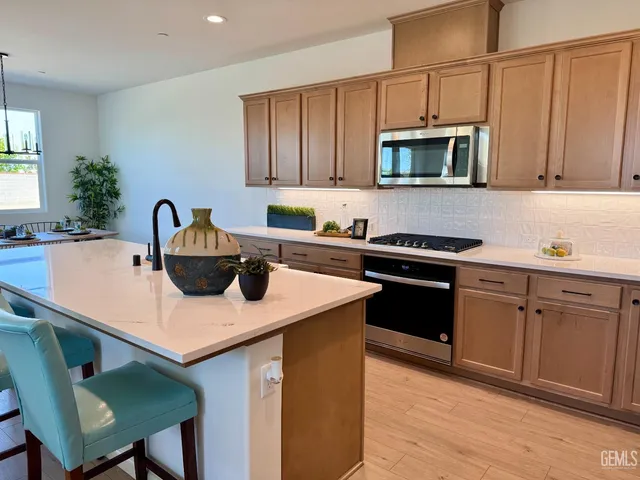 a kitchen with stainless steel appliances a sink a microwave a refrigerator and cabinets