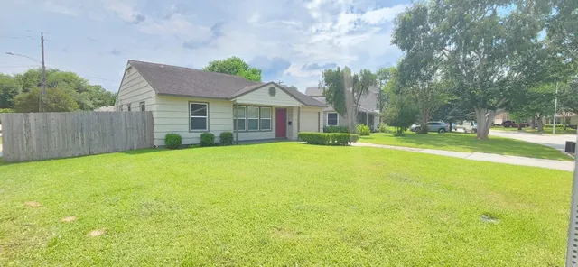 a view of a house with a big yard and large trees
