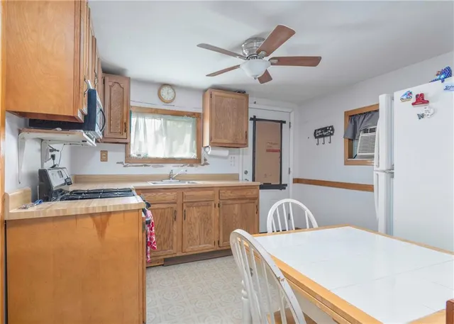 a kitchen with stainless steel appliances granite countertop a stove top oven a sink a dining table and chairs with wooden floor