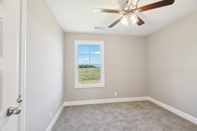 an empty room with windows and fan