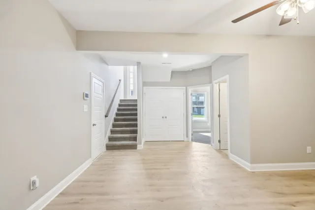 a view of an empty room with wooden floor and stairs