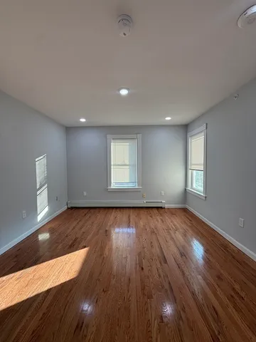 a view of an empty room with wooden floor and window