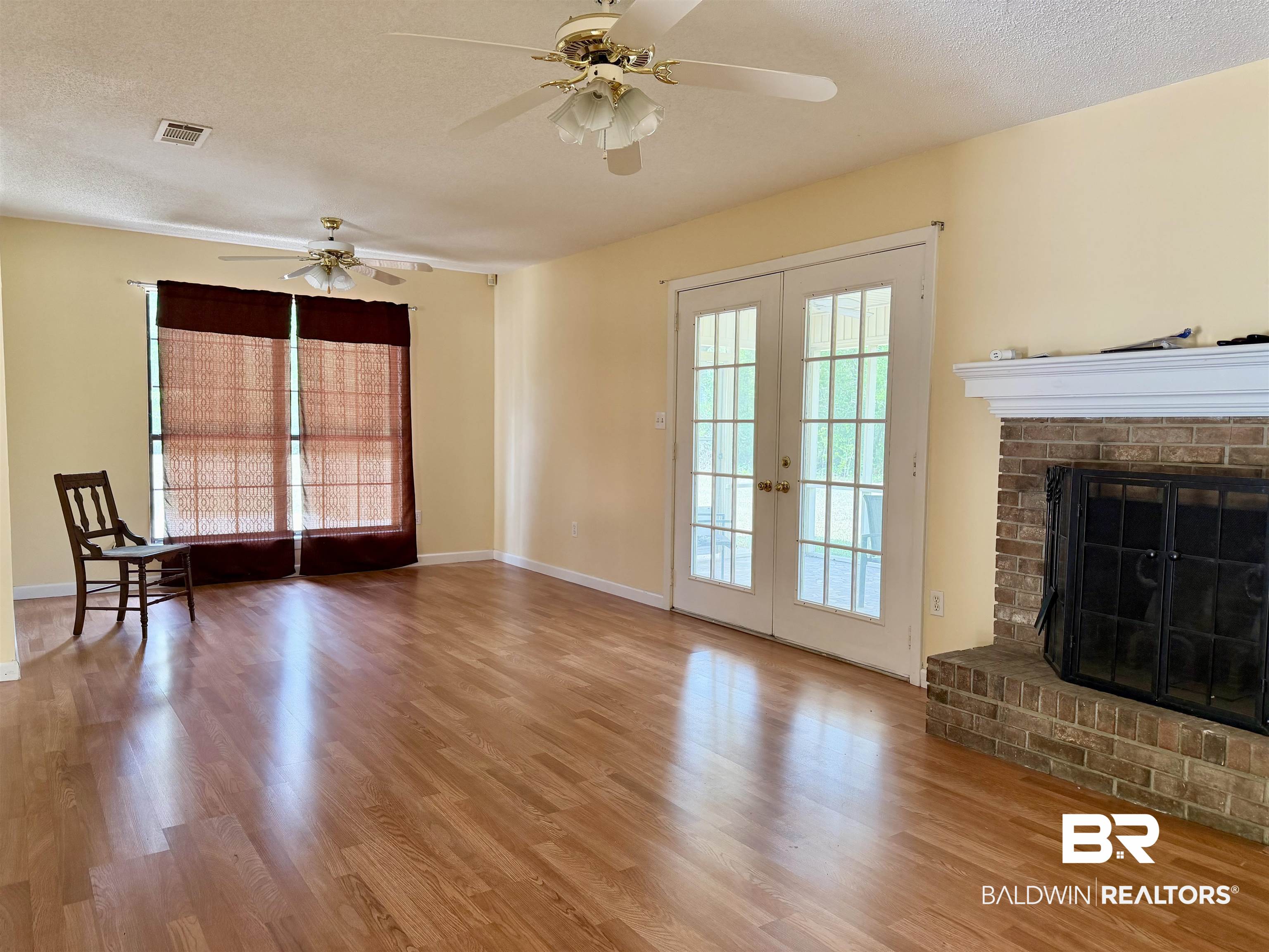 294 Wolf Log Road Flomaton, AL 36441 - Photo 5 of 14 Unfurnished living room with french doors, a textured ceiling, light wood-style floors, a fireplace, and ceiling fan