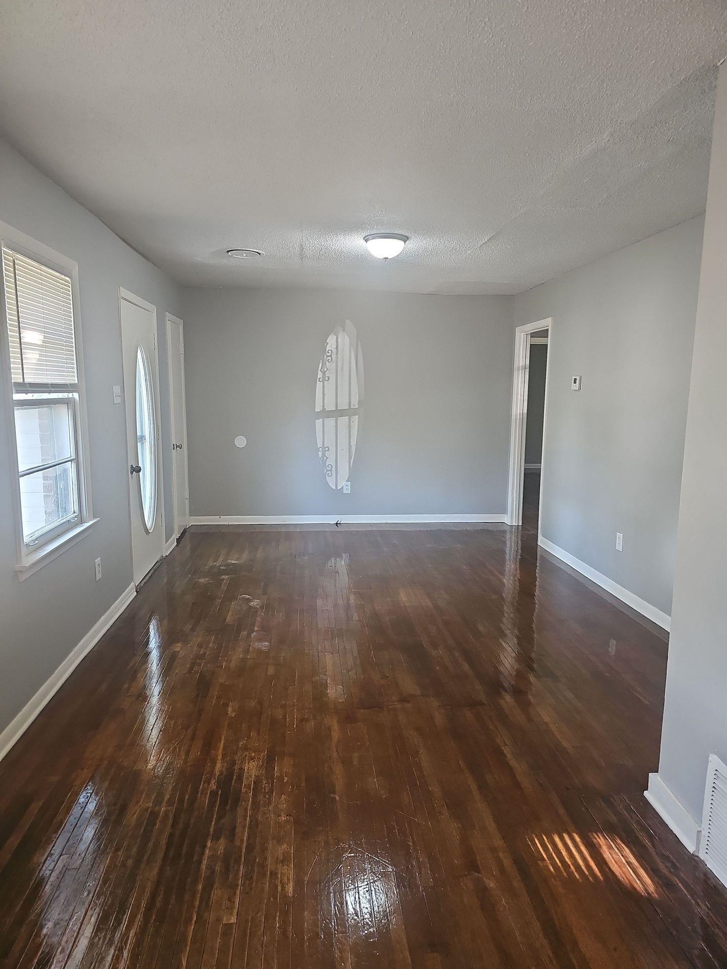 1772 Carlyle Road Memphis, TN 38127 - Photo 3 of 14 Unfurnished living room with dark wood finished floors, baseboards, and a textured ceiling