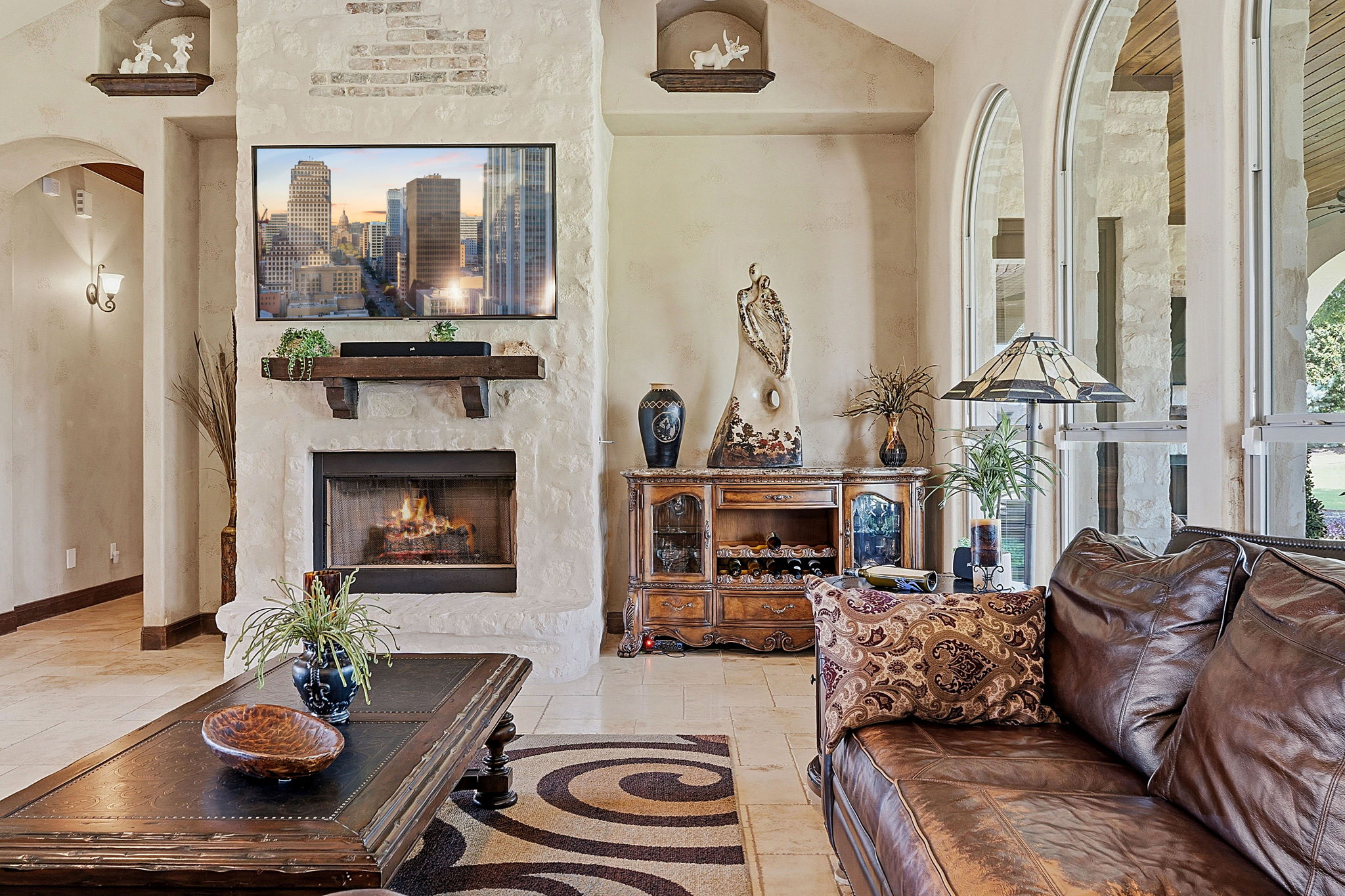 816 Brave Face Street Leander, TX 78641 - Photo 4 of 40 A cozy living area showcases a natural stone fireplace and floor-to-ceiling arched windows.