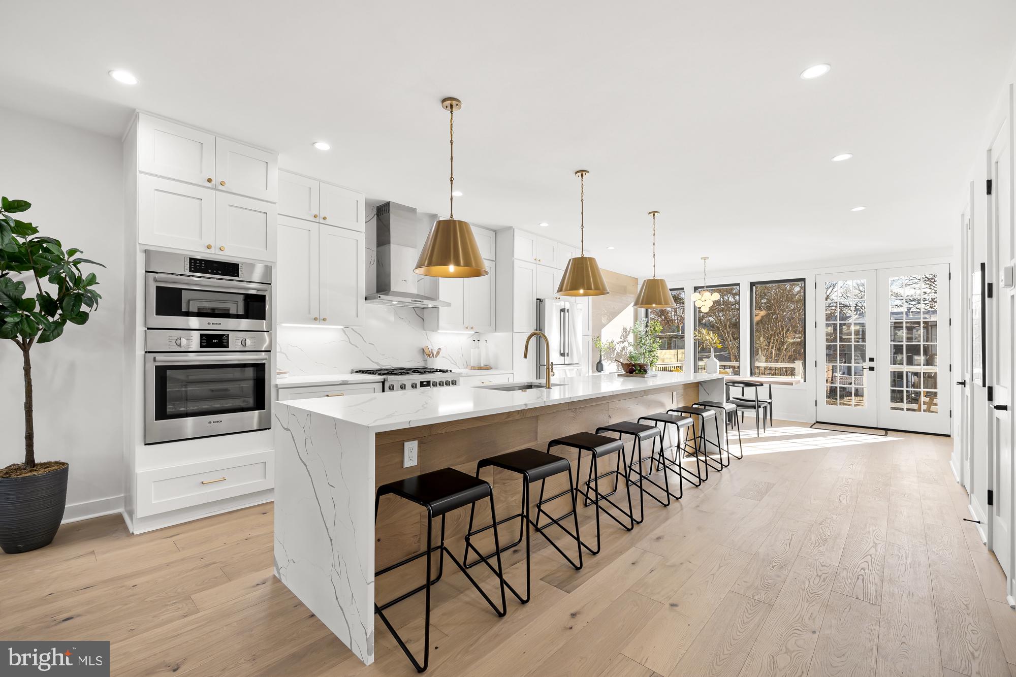 a open kitchen with stainless steel appliances kitchen island granite countertop a stove a sink a refrigerator and a dining table with wooden floor