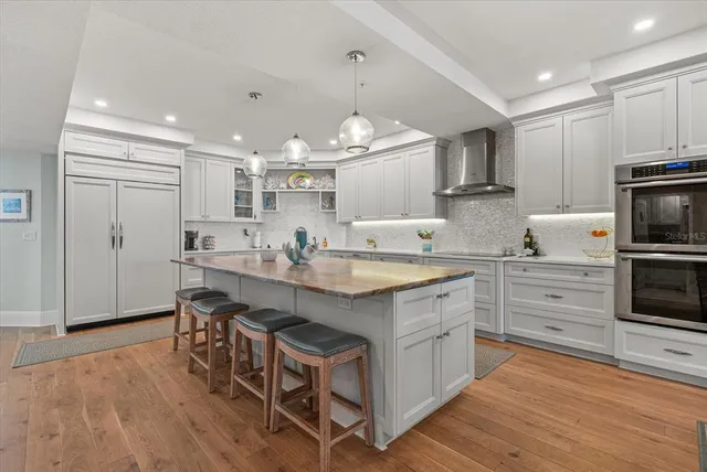 a large kitchen with cabinets chairs and wooden floor