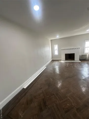 an empty room with wooden floor fireplace and windows
