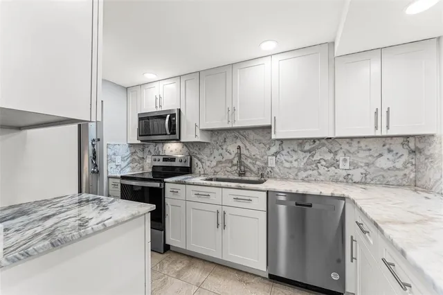 a kitchen with granite countertop white cabinets and stainless steel appliances
