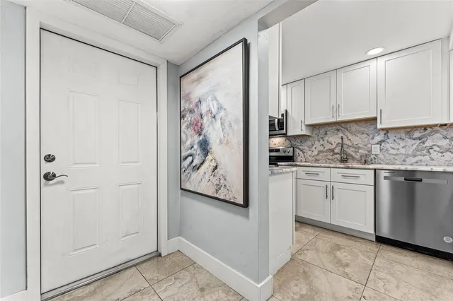 a kitchen with stainless steel appliances granite countertop white cabinets and refrigerator