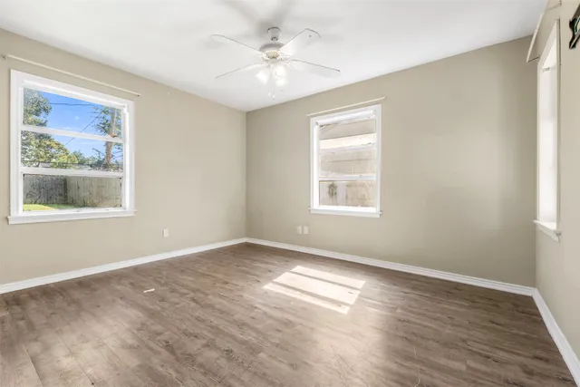 a view of empty room with wooden floor and fan